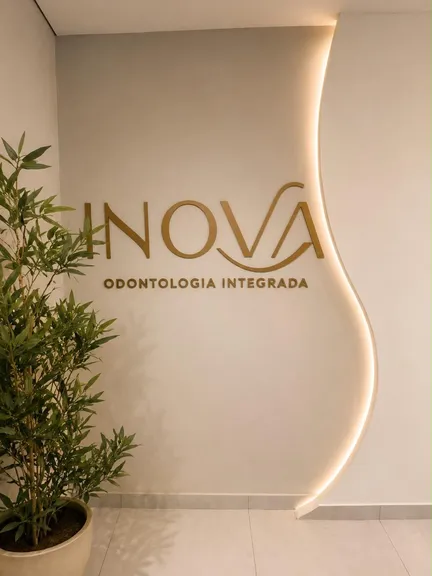 Letreiro dourado da INOVA Odontologia Integrada iluminado na parede da recepção, no Eldorado